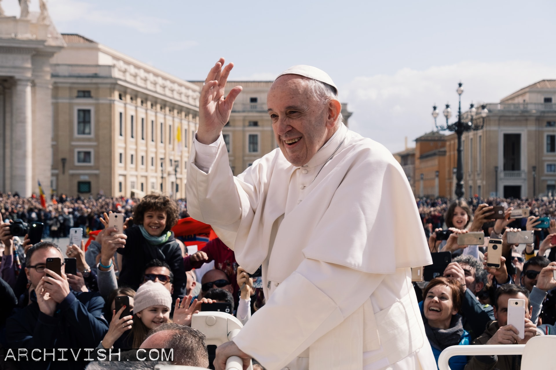 The pope greets the people from an open popemobile